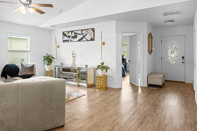 living room with hardwood / wood-style flooring, ceiling fan, and vaulted ceiling