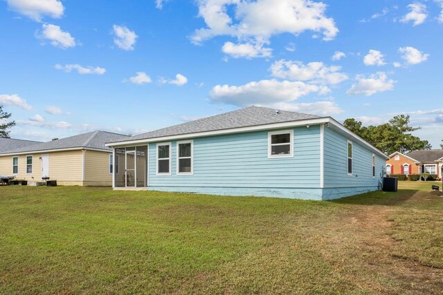 rear view of property with central AC unit, a lawn, and a sunroom