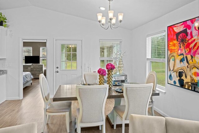 dining space with light wood-type flooring, lofted ceiling, and a notable chandelier