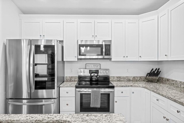 kitchen with white cabinetry, appliances with stainless steel finishes, and light stone counters