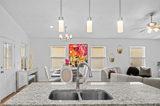 kitchen with light stone countertops, sink, pendant lighting, and lofted ceiling