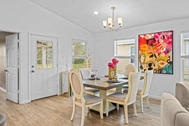 dining area with light hardwood / wood-style floors, a notable chandelier, and vaulted ceiling