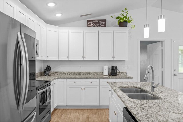 kitchen with stainless steel appliances, vaulted ceiling, sink, white cabinetry, and decorative light fixtures