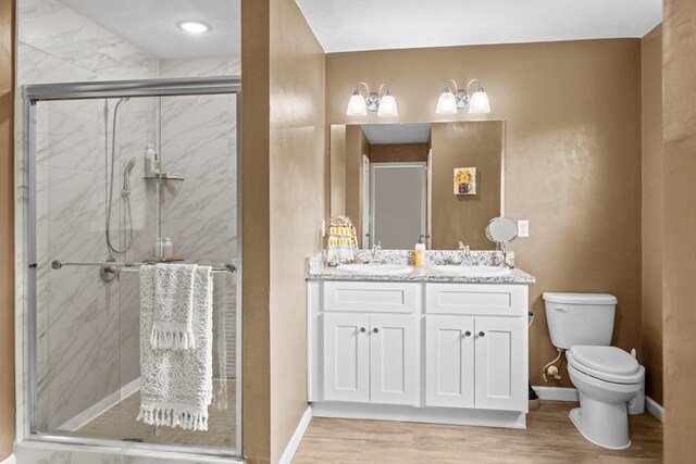 bathroom with hardwood / wood-style floors, a shower with shower door, vanity, and toilet