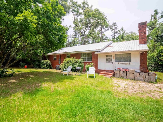 3364 NW 66th Blvd, Jennings, FL 32053 - back of house with a chimney, a lawn, brick siding, and metal roof