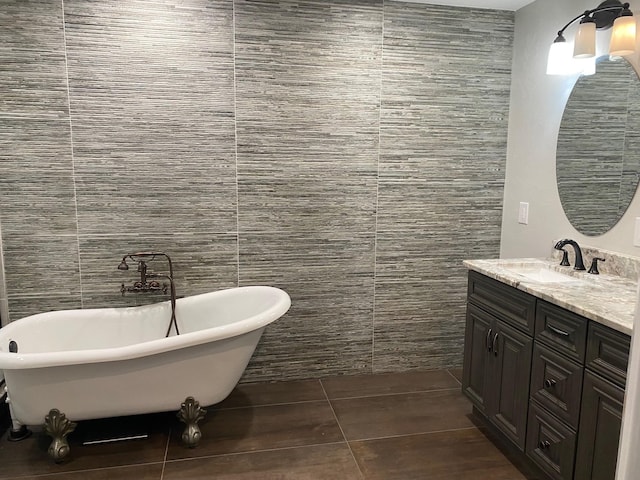 bathroom with a bathtub, vanity, tile walls, and tile patterned flooring