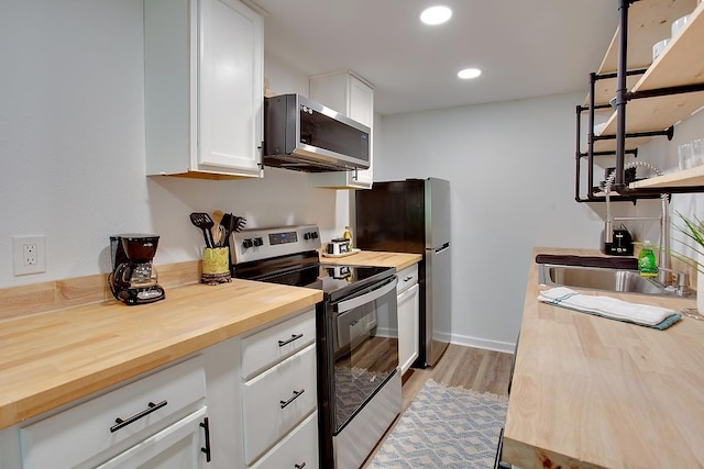 kitchen featuring stainless steel appliances, sink, white cabinets, light hardwood / wood-style flooring, and wooden counters