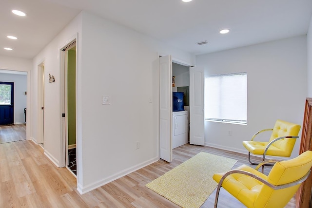 living area featuring light wood-type flooring, washer / clothes dryer, and a wealth of natural light