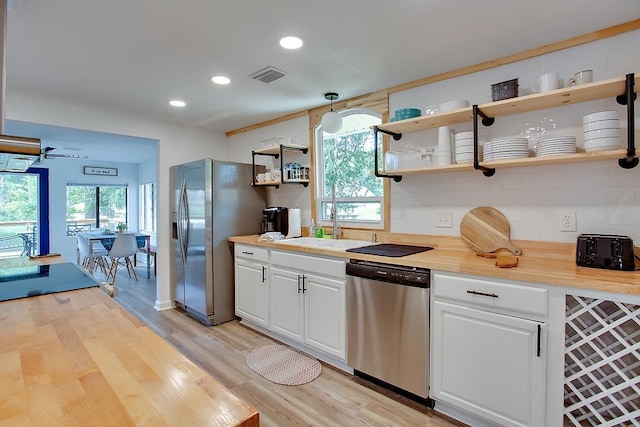 kitchen with wooden counters, white cabinets, appliances with stainless steel finishes, and hanging light fixtures