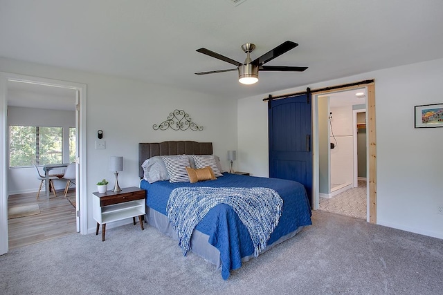 bedroom featuring ceiling fan, a barn door, and carpet flooring