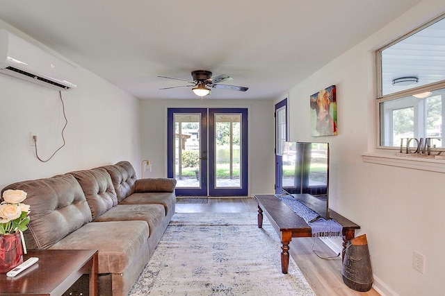 living room featuring ceiling fan, a wall mounted AC, french doors, and light wood-type flooring