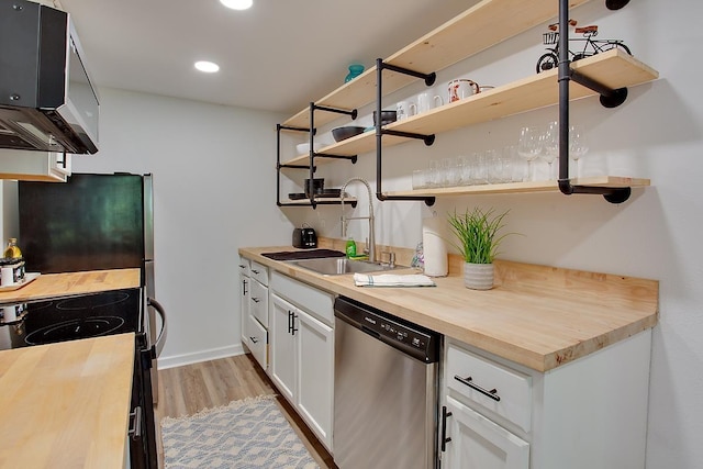 kitchen featuring stainless steel appliances, light wood-type flooring, butcher block countertops, sink, and white cabinetry