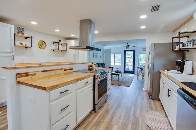 kitchen featuring island range hood, wood counters, white cabinetry, appliances with stainless steel finishes, and ceiling fan