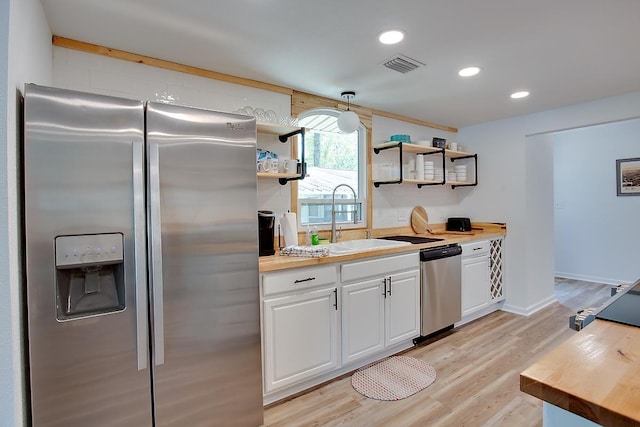 kitchen featuring sink, white cabinets, light wood-type flooring, wood counters, and appliances with stainless steel finishes