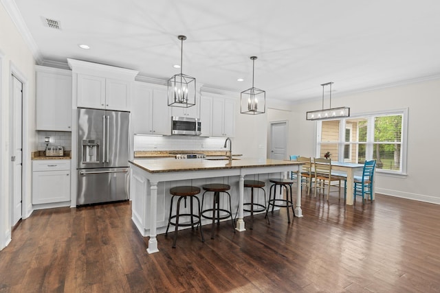 kitchen with appliances with stainless steel finishes, a breakfast bar, a center island with sink, and white cabinets