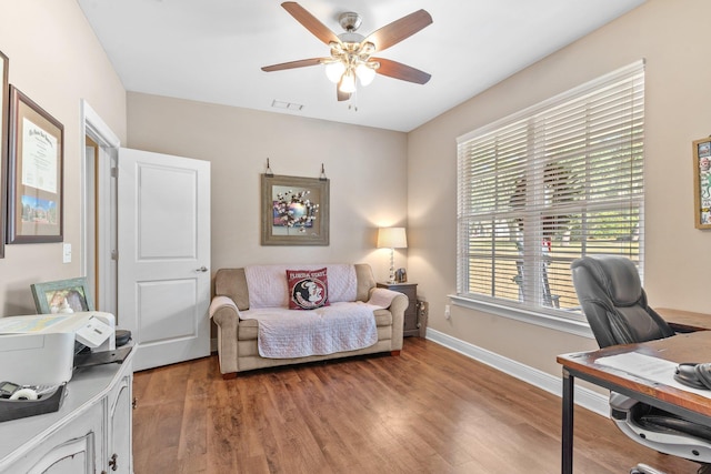 interior space with baseboards, visible vents, ceiling fan, and wood finished floors