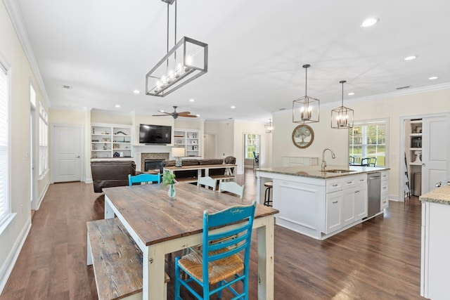 dining area with built in features, a glass covered fireplace, dark wood-style floors, crown molding, and recessed lighting