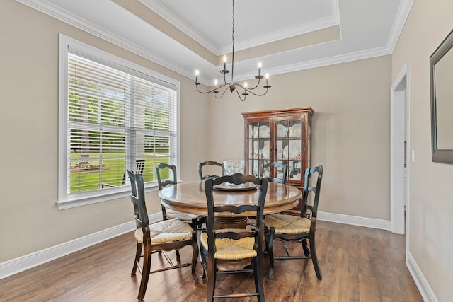 dining room featuring crown molding, wood finished floors, a raised ceiling, and baseboards