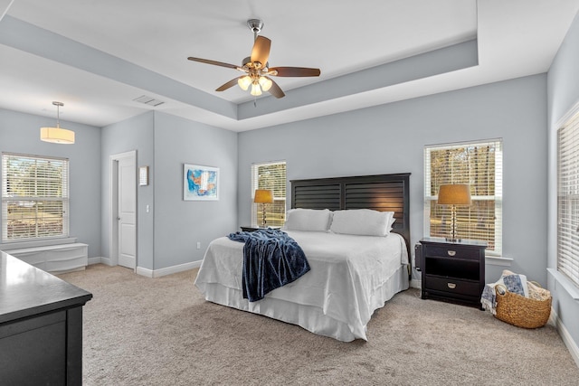 bedroom featuring light carpet, a tray ceiling, visible vents, and baseboards