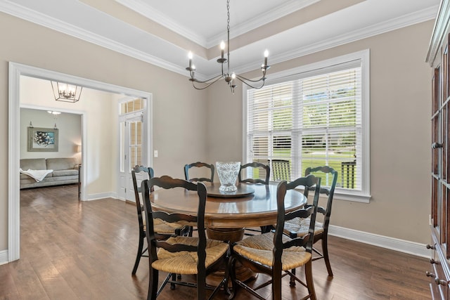 dining space featuring baseboards, a raised ceiling, dark wood-type flooring, crown molding, and a notable chandelier