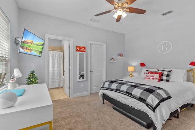 bedroom featuring ceiling fan, ensuite bath, visible vents, and light colored carpet