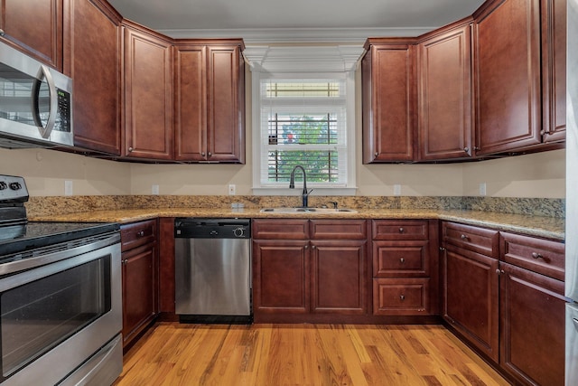 kitchen with crown molding, sink, appliances with stainless steel finishes, light hardwood / wood-style floors, and light stone counters