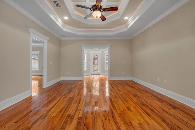 unfurnished room with light wood-type flooring, a raised ceiling, ceiling fan, and crown molding