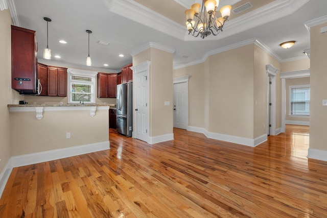 kitchen with kitchen peninsula, stainless steel fridge with ice dispenser, a wealth of natural light, and ornamental molding