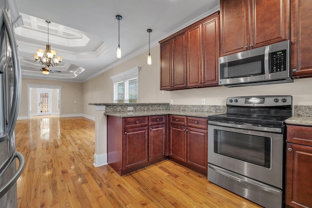 kitchen with light stone counters, stainless steel appliances, a tray ceiling, crown molding, and decorative light fixtures