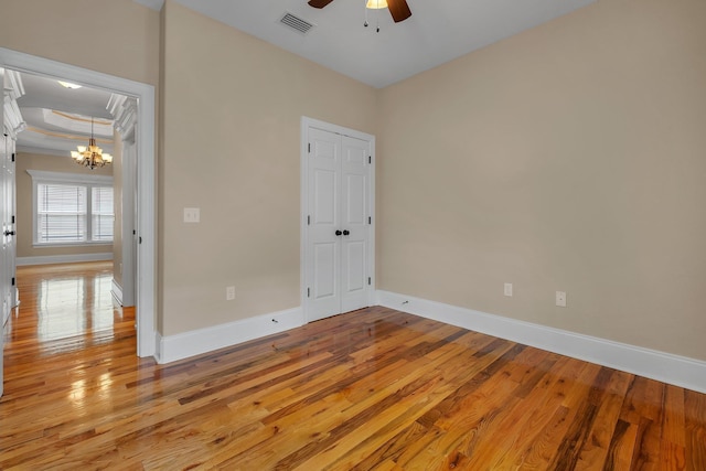 unfurnished room with ceiling fan with notable chandelier, light hardwood / wood-style floors, and ornamental molding