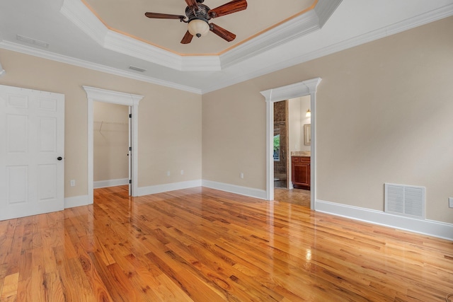 spare room featuring light hardwood / wood-style floors, a raised ceiling, ceiling fan, and crown molding