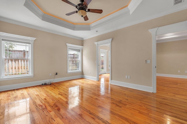 spare room with a raised ceiling, crown molding, light hardwood / wood-style flooring, and ceiling fan