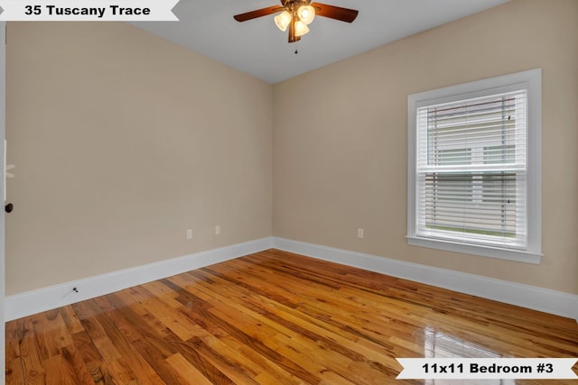 empty room with a wealth of natural light, ceiling fan, and hardwood / wood-style flooring