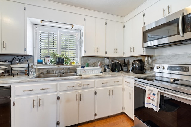 kitchen with appliances with stainless steel finishes, sink, and white cabinets