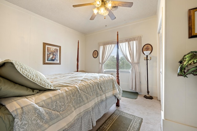 carpeted bedroom featuring ceiling fan, ornamental molding, and a textured ceiling