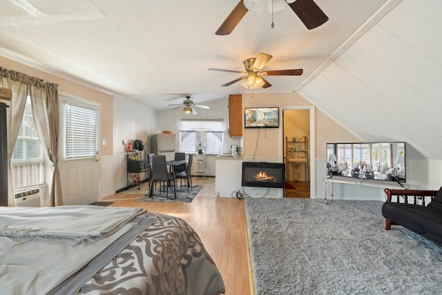 bedroom with cooling unit, lofted ceiling, and light hardwood / wood-style flooring