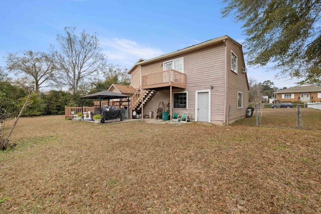 back of property featuring a gazebo, a wooden deck, and a lawn