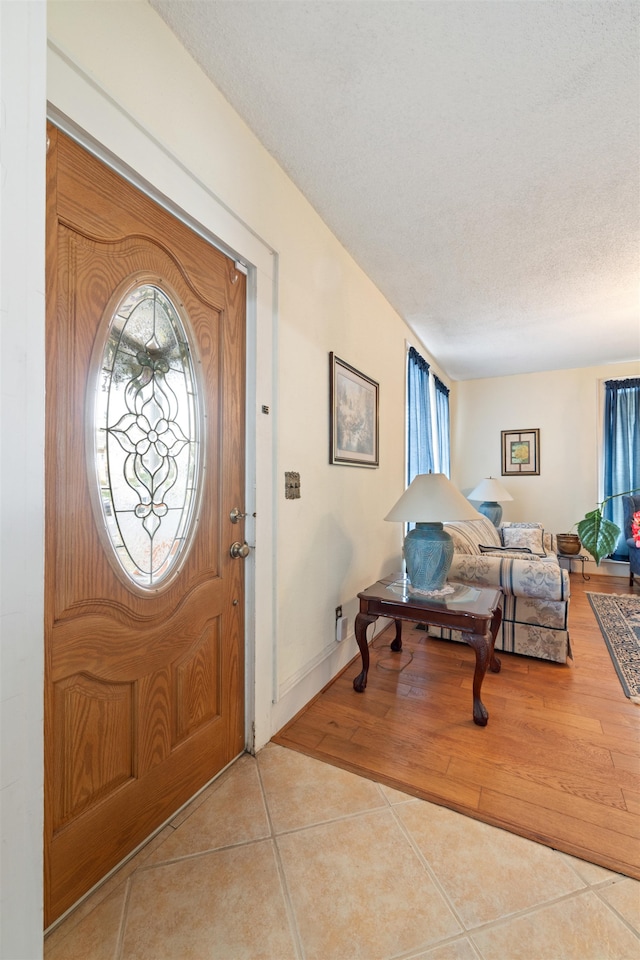 foyer entrance with a textured ceiling and light tile patterned floors