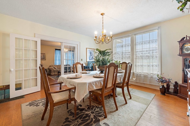 dining space with a notable chandelier, light hardwood / wood-style floors, and a textured ceiling