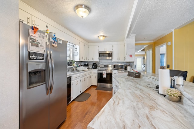 kitchen with white cabinetry, tasteful backsplash, wood-type flooring, stainless steel appliances, and light stone countertops