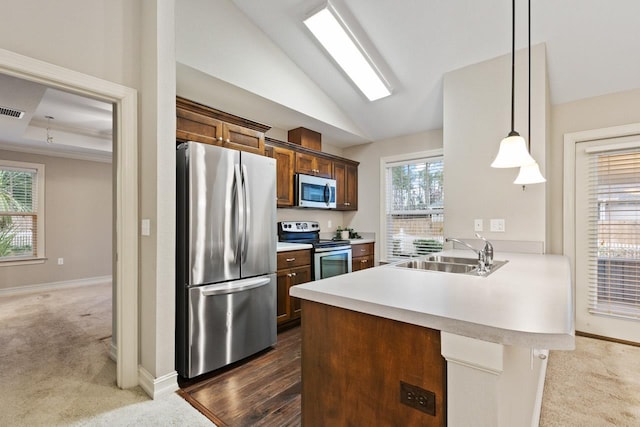 kitchen featuring stainless steel appliances, hanging light fixtures, a peninsula, and a sink