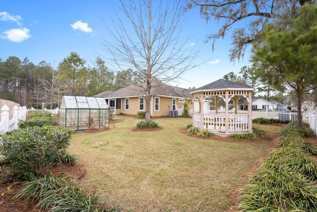 view of yard with an outbuilding, central AC unit, a greenhouse, a fenced backyard, and a gazebo