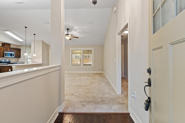 entryway featuring light wood-style flooring, baseboards, a ceiling fan, and light colored carpet