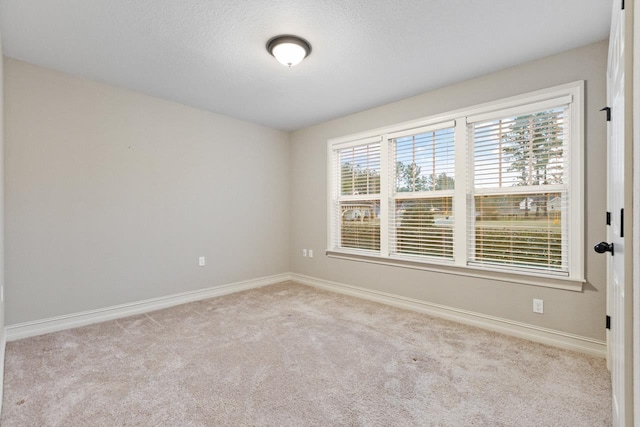 unfurnished room featuring baseboards and light colored carpet