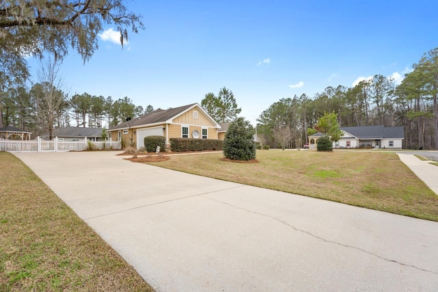 view of front of property featuring a garage, fence, driveway, board and batten siding, and a front yard