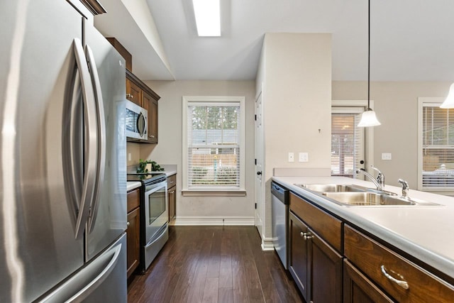 kitchen featuring a sink, stainless steel appliances, light countertops, and pendant lighting