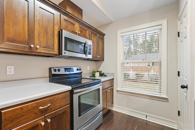 kitchen featuring stainless steel appliances, dark wood-style flooring, baseboards, light countertops, and brown cabinetry