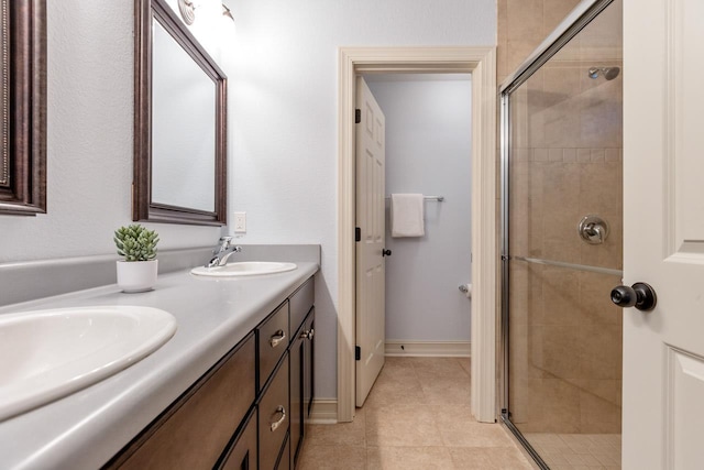 full bath featuring a stall shower, a sink, baseboards, and double vanity