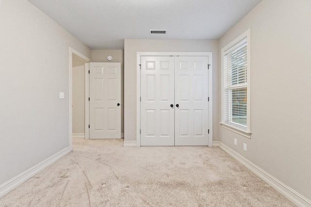 unfurnished bedroom with baseboards, multiple windows, visible vents, and light colored carpet