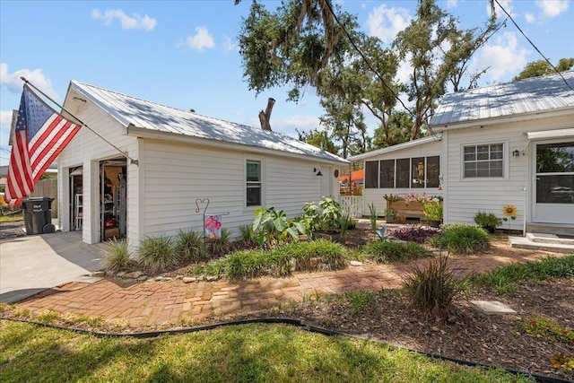 514 N Calhoun St, Perry, FL 32347 - view of side of property featuring a metal roof, an outbuilding, a sunroom, driveway, and a garage